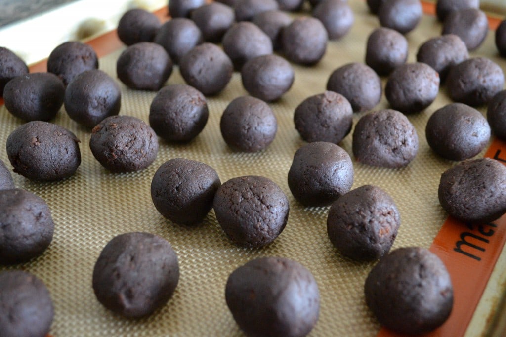 Chocolate truffles on baking sheet with parchment paper, ready for coating or rolling. Handcrafted, rich, and decadent sweets perfect for gifts or special occasions. Ideal for chocolate lovers.