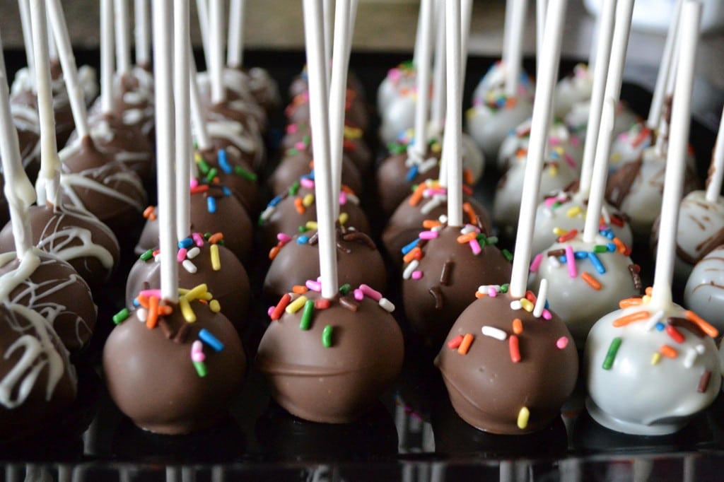 Chocolate and white cake pops with colorful sprinkles on sticks, perfect for parties and celebrations at Stuck On Sweet.
