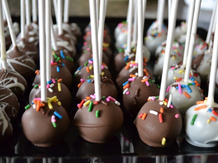 Chocolate and white cake pops with colorful sprinkles on sticks, perfect for parties and celebrations at Stuck On Sweet.