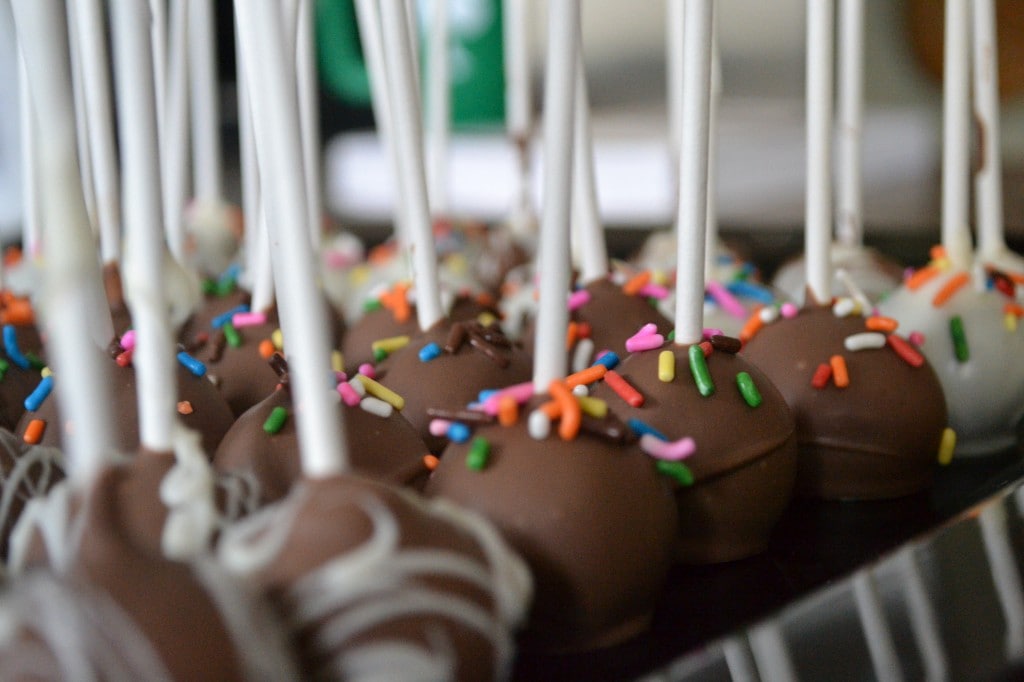 Chocolate cake pops with colorful sprinkles on sticks for dessert or celebration.