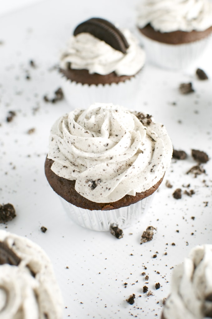 Creamy cookies and cream cupcakes with chocolate base and whipped frosting topped with Oreo cookie pieces. Perfect for chocolate and cookie lovers, these cupcakes are a delicious dessert treat.