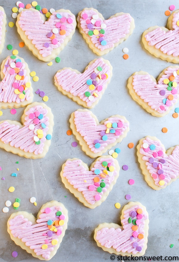 Heart-shaped sugar cookies with pink frosting and colorful confetti sprinkles, perfect for Valentine's Day or celebrations.