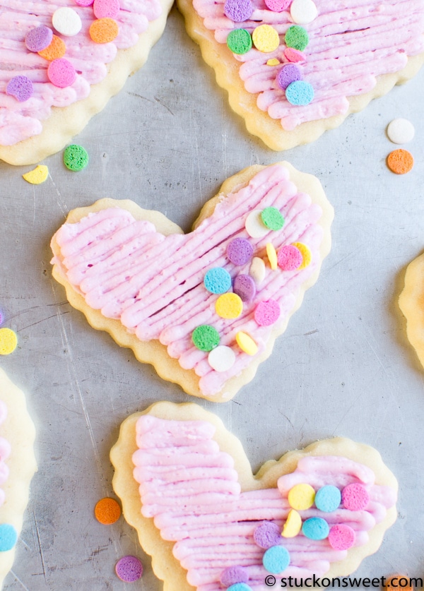 Heart-shaped sugar cookies with pink icing and colorful sprinkle toppings, perfect for Valentine's Day or sweet treats, bakery cookies, decorated sugar cookies.