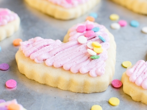 Heart-shaped sugar cookies with pink frosting and colorful sprinkles for Valentine's Day or special occasions. Perfect for sweet tooth cravings and cookie decorating ideas.