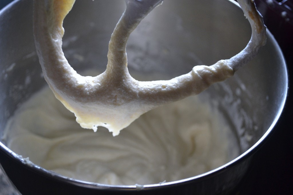 Buttercream frosting in a mixing bowl with a paddle attachment, smooth and creamy texture, dessert baking, sweet frosting, baking ingredients, dessert decorating.