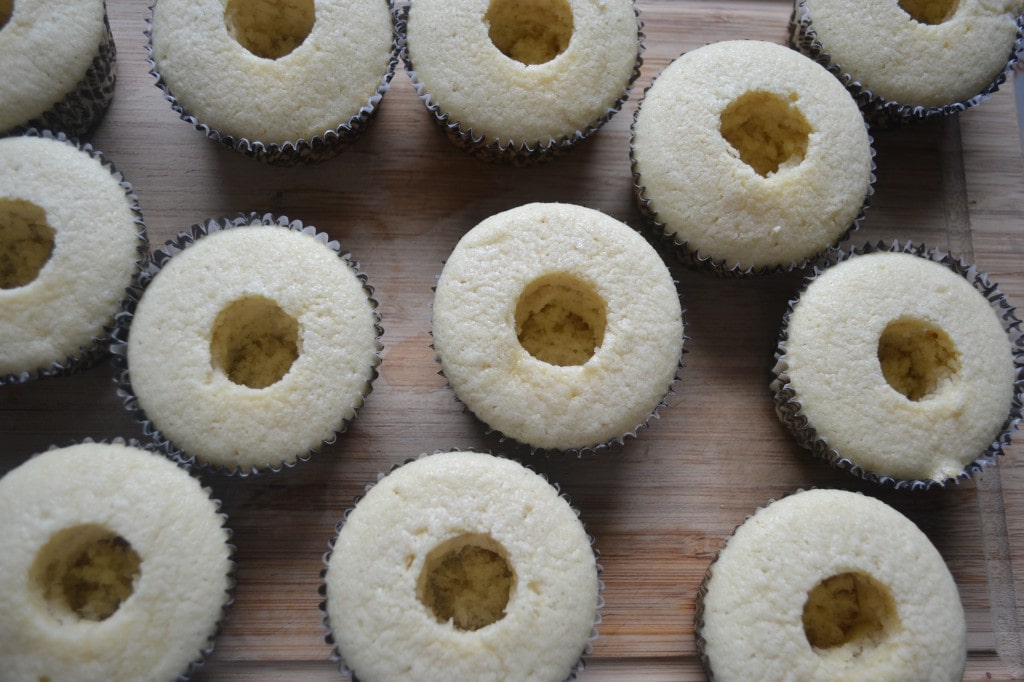 Light yellow vanilla cupcakes with a central hole, arranged on a wooden surface, perfect for baking and dessert lovers.