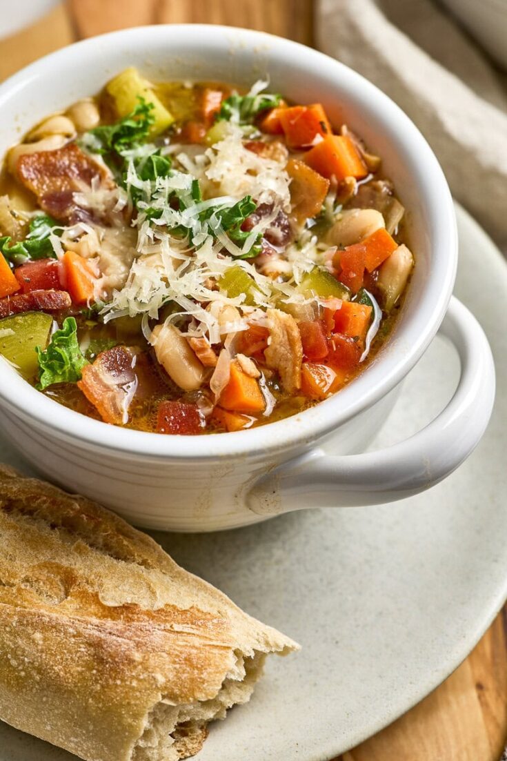 Tuscan Kale and White Bean Soup with shredded cheese, and fresh herbs served with fresh bread.