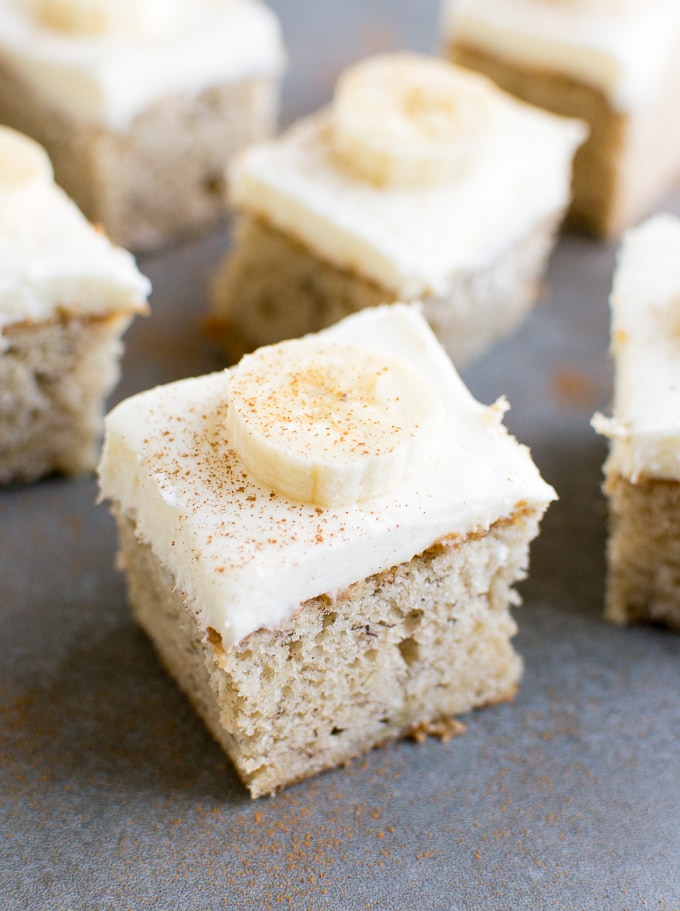 Butter cake squares with cream cheese frosting and banana slices, close-up view.