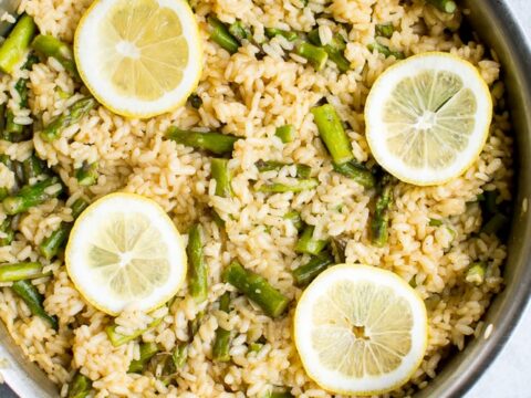 Parmesan lemon risotto with asparagus in a skillet, garnished with lemon slices, light and flavorful Asian-inspired dish. Perfect for lunch or dinner, easy to make.