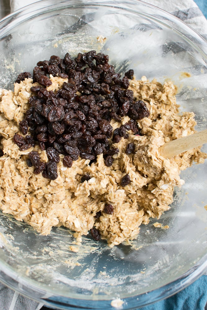 Golden raisins and cookie dough mixture in a glass bowl for homemade baked goods.