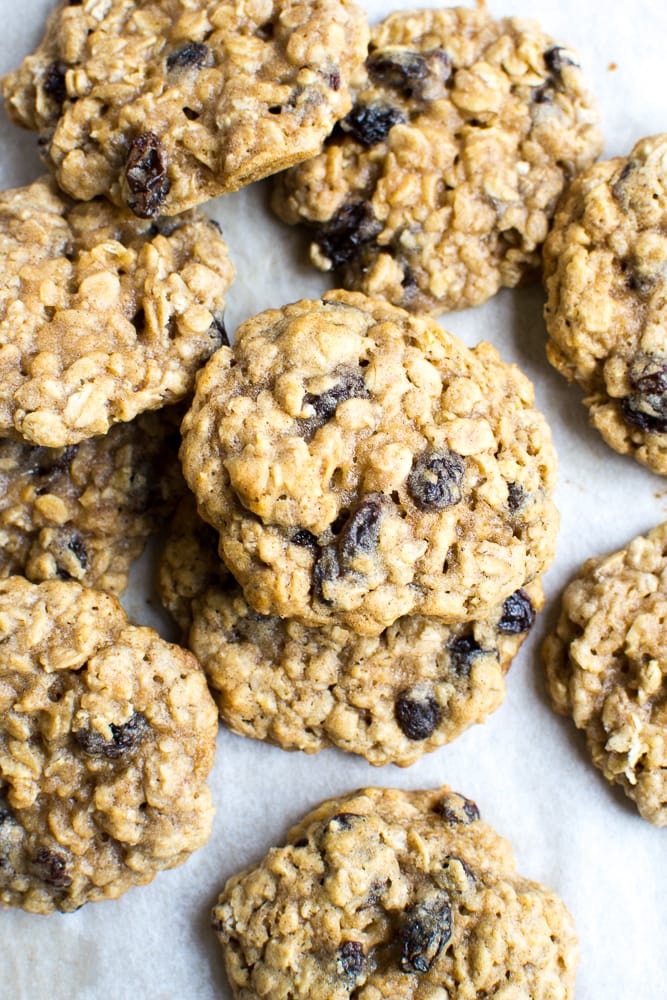 Chewy oatmeal raisin cookies with oats and dried fruit on parchment paper, featuring a golden-brown, crunchy exterior and soft interior. Perfect for snacking or dessert.