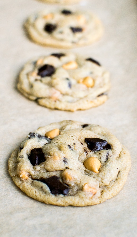 Chocolate chip cookies with peanut butter chips on parchment paper.