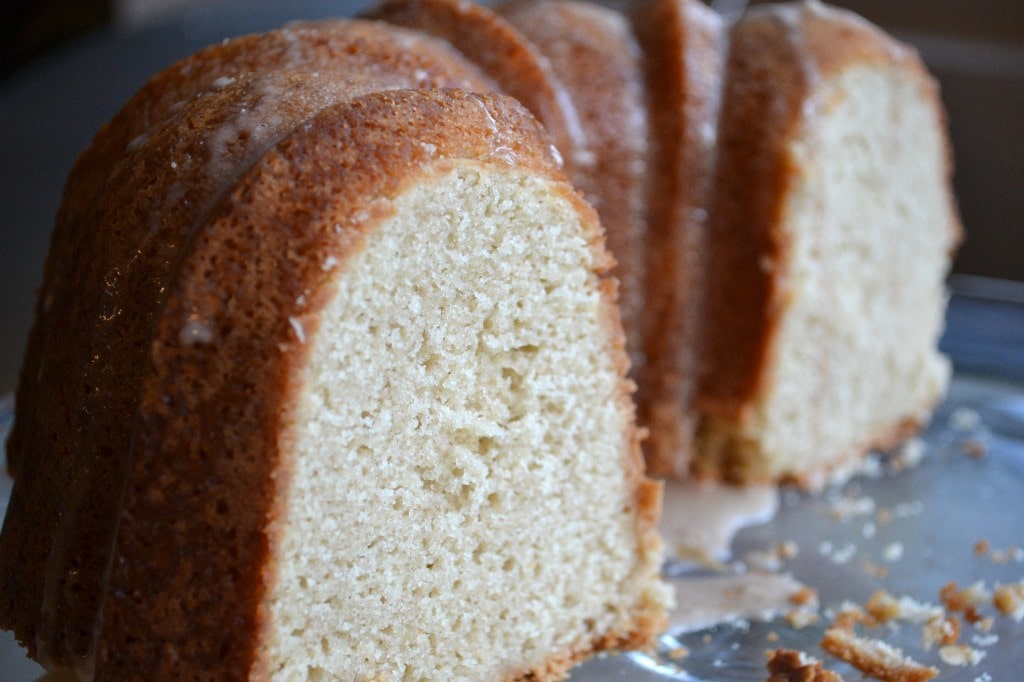 Moist vanilla bundt cake with a glossy glaze topping, served on a black plate, showcasing its fluffy interior and appealing golden crust, perfect for dessert or teatime treats.