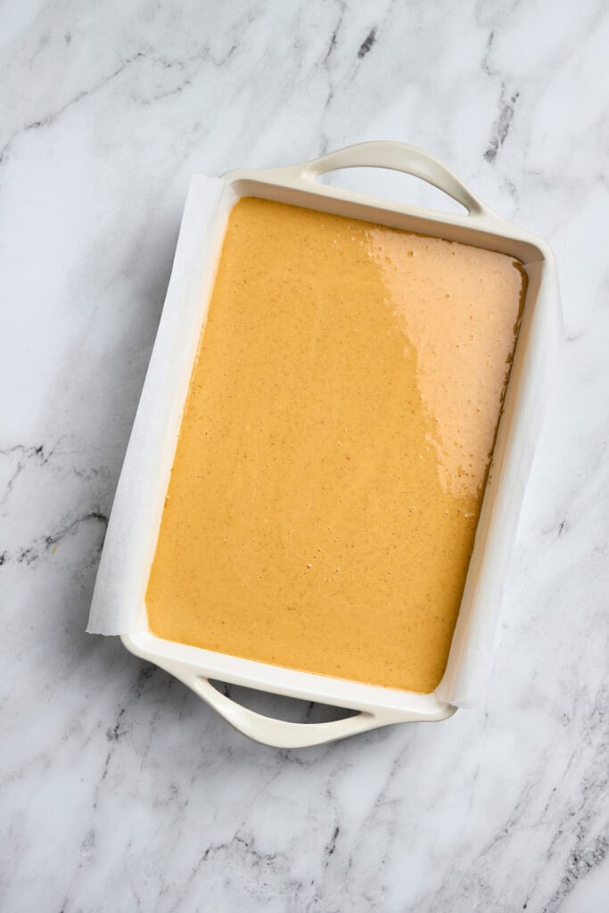 Creamy caramel sauce in a white baking dish on marble surface for dessert recipes.