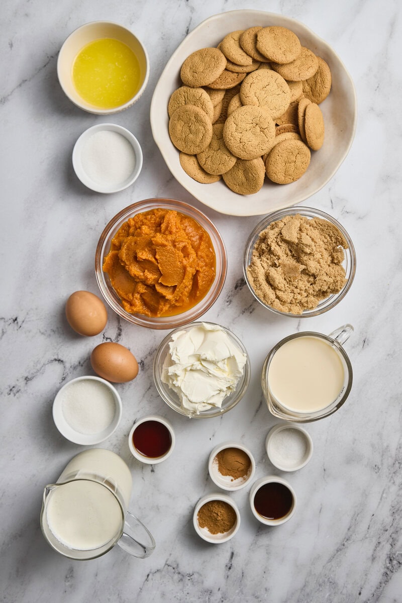 Sweet potato cookies ingredients on marble surface, including gingerbread cookies, eggs, butter, cream, sugar, spices, and milk, ready for baking.