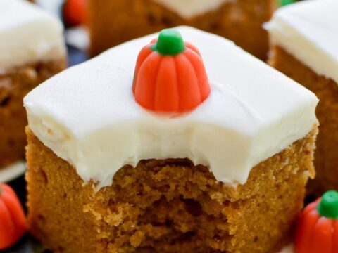 Delicious pumpkin bars with cream cheese frosting and festive candy decorations, perfect for fall desserts or holiday celebrations.
