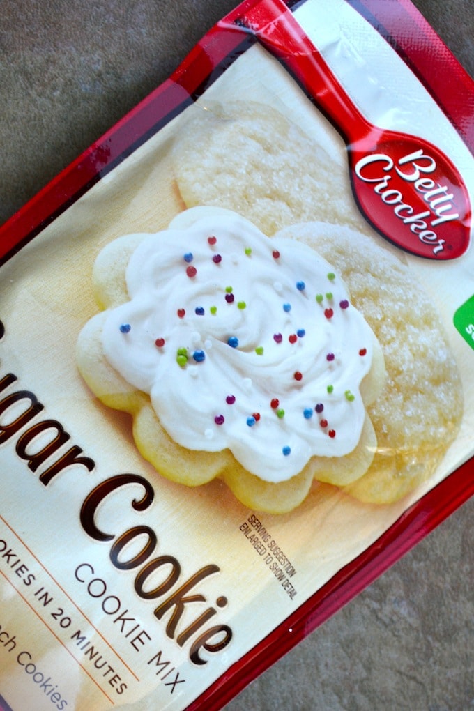 Creamy vanilla sugar cookie with colorful sprinkles topped with swirled frosting from Stuck On Sweet, perfect for baking and decorating.