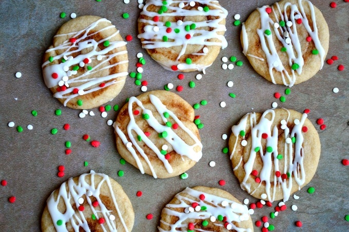 Colorful holiday sugar cookies with white icing and red, green, and white sprinkles on a parchment paper background, festive and cheerful dessert for celebrations.