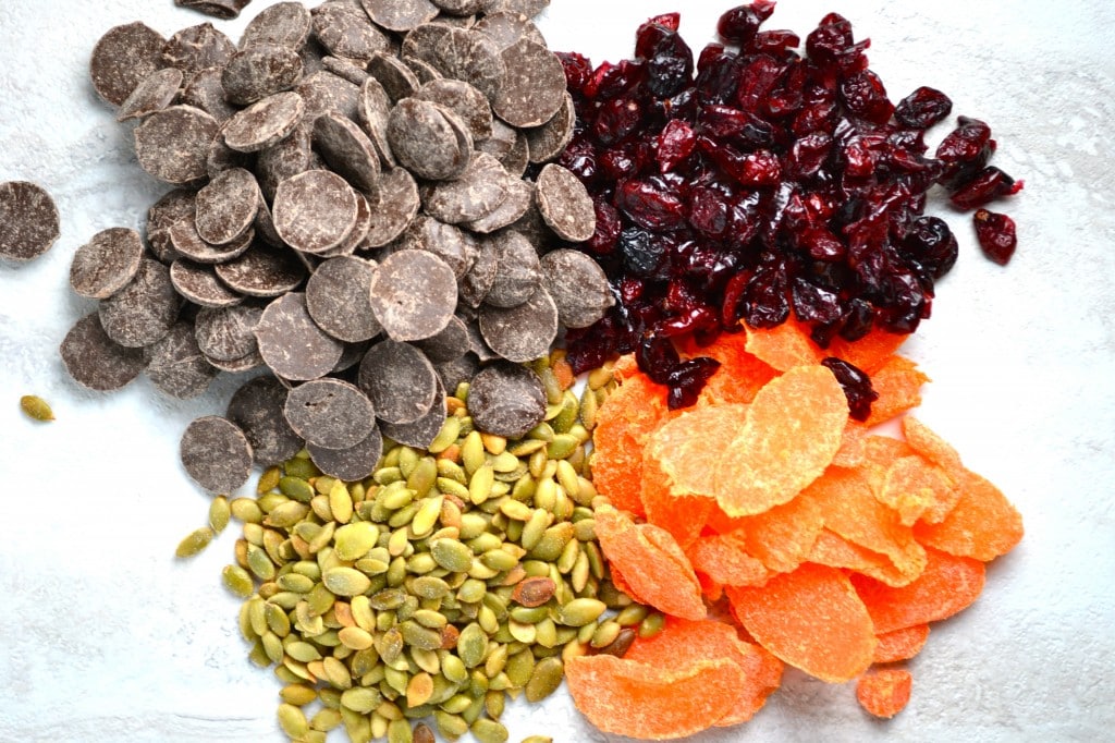 Decadent chocolate chips, dried cranberries, pumpkin seeds, and apricot slices shown in this colorful close-up image, perfect for baking and dessert recipes.