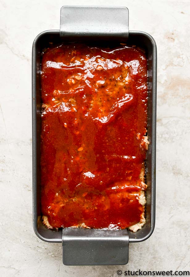 Rich homemade meatloaf topped with tomato sauce in a baking pan, perfect for comfort food meals.