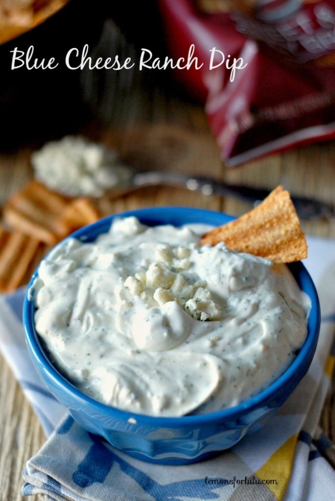 Creamy blue cheese ranch dip with crumbled blue cheese and a tortilla chip in a blue bowl, perfect for snacking or dipping, on a rustic wooden surface.