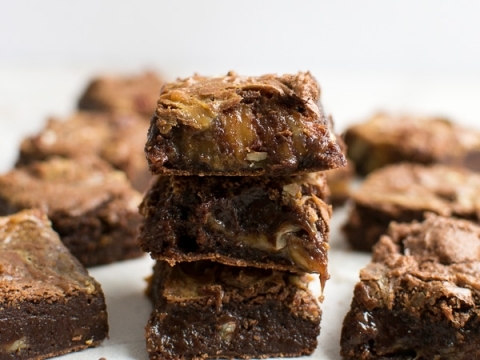 Stacked homemade brownie bites with chocolate chips on white background.