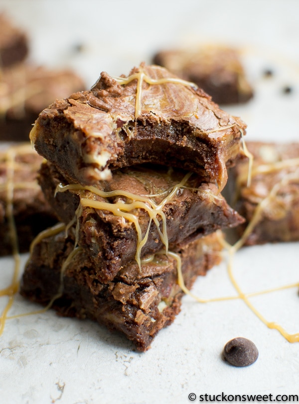 Rich chocolate brownie bars drizzled with melted white chocolate, stacked on a white surface. Perfect for dessert lovers and brownie enthusiasts.