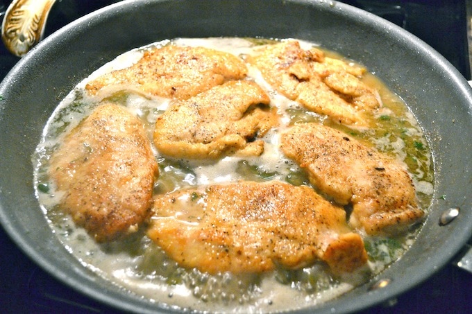 Golden crispy fried chicken cooking in a skillet with bubbling oil, featuring seasoned breading and savory aroma.