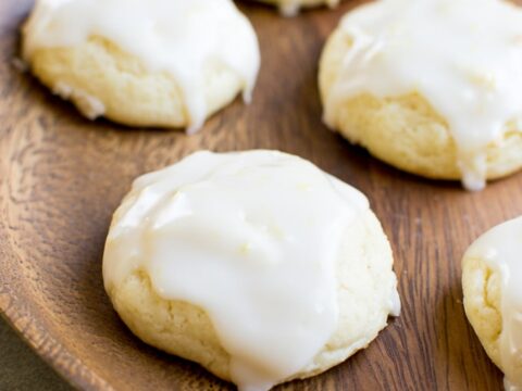 Lemon cream cheese cookies with white glaze on a wooden plate.