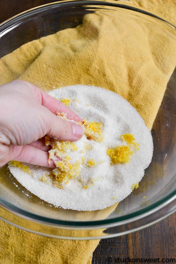 Sweet corn kernels being coated in sugar in a glass mixing bowl for a homemade sweet treat.