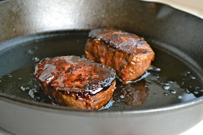 Juicy steak cooking in a black skillet with caramelized glaze for flavorful sweet-savory dish.