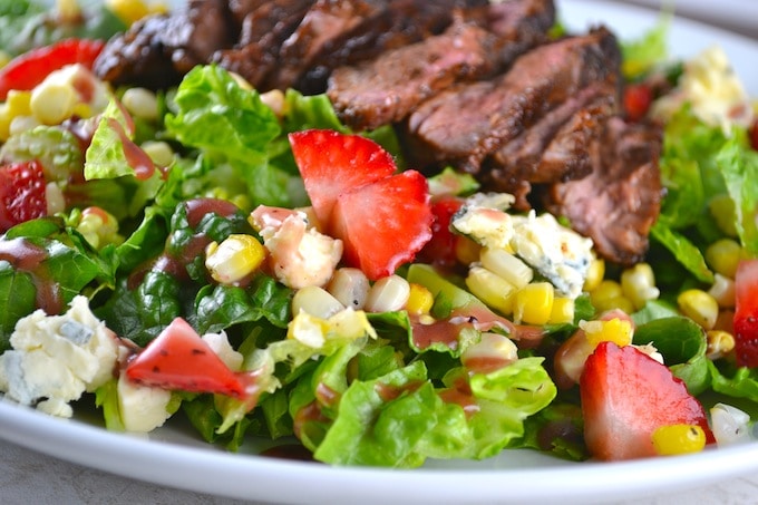 Fresh garden salad with grilled steak, strawberries, corn, and blue cheese crumbles, perfect for healthy eating and flavorful meals.