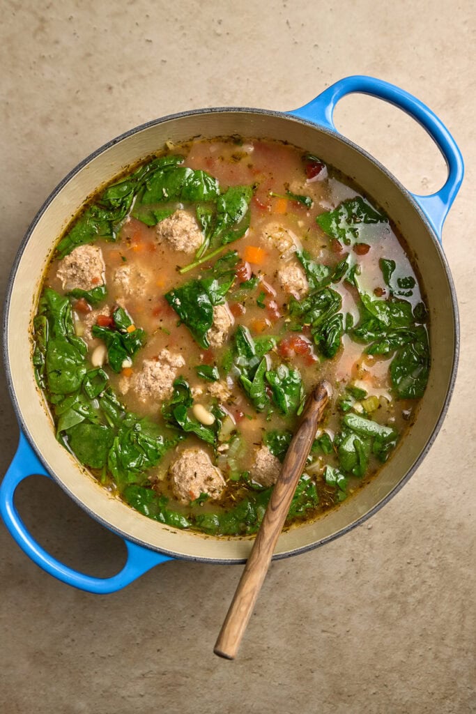 Hearty homemade chicken and spinach soup in a blue pot, fresh ingredients, rustic comfort food, nutritious broth, and wholesome meal.