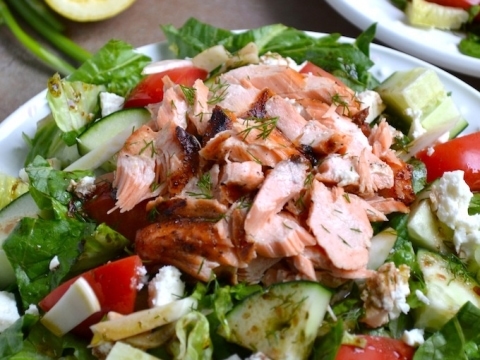 Grilled salmon salad with fresh vegetables, cucumbers, tomatoes, and greens on white plates, lemon wedges in background, healthy and flavorful meal, Stuck On Sweet.