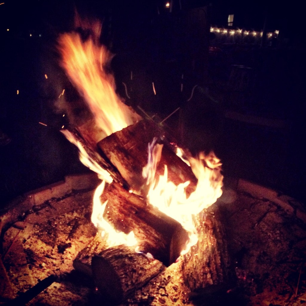 Fire pit with burning logs at night, cozy outdoor fire, warm campfire for social gathering, outdoor entertainment, night time fire ambiance.