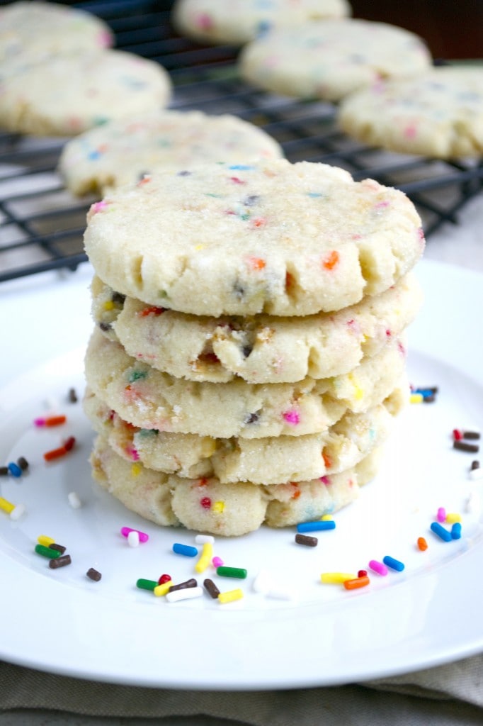 Buttery sugar cookies with colorful sprinkles stacked on a white plate, perfect for celebrations and parties. Delicious festive cookies made with fun, vibrant sprinkles.