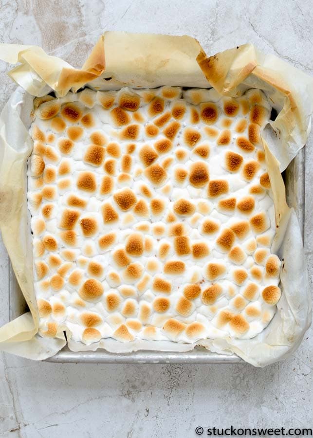 Fluffy toasted marshmallow topping on a homemade s'mores dessert bar in a baking pan.