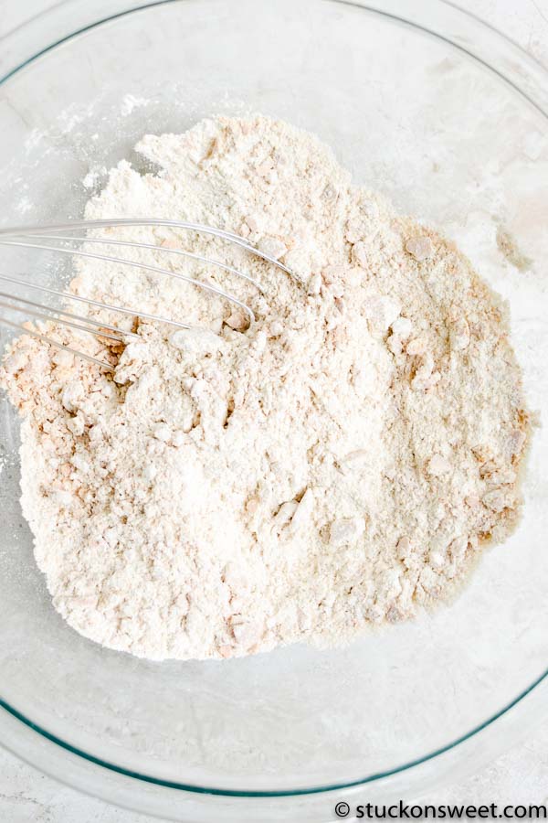Flour in a glass mixing bowl with a whisk for baking or cooking recipes.