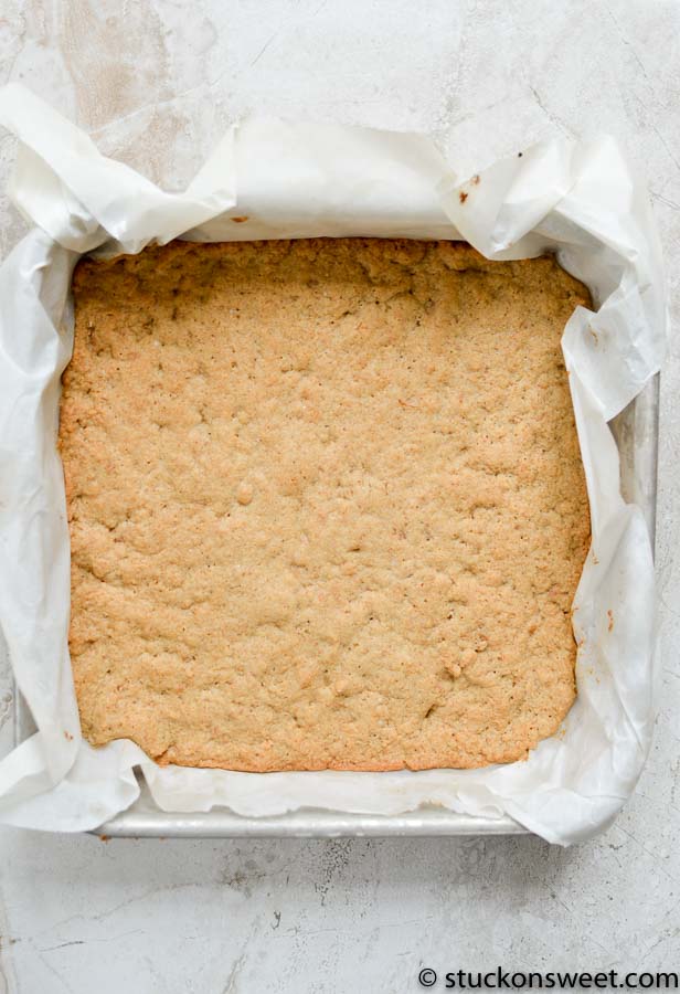 Soft baked cookie bar in parchment-lined baking pan, ready to be sliced into sweet, chewy treats, perfect for dessert or snack.
