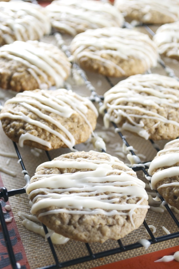 Soft oatmeal cookies drizzled with white chocolate on a cooling rack, freshly baked and perfect for dessert or snacks.