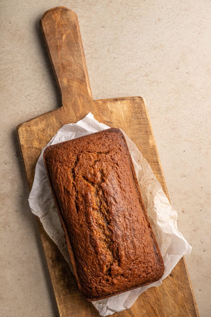 Butter cake loaf on a wooden serving board with parchment paper, perfect for homemade baked goods and sweet treats.