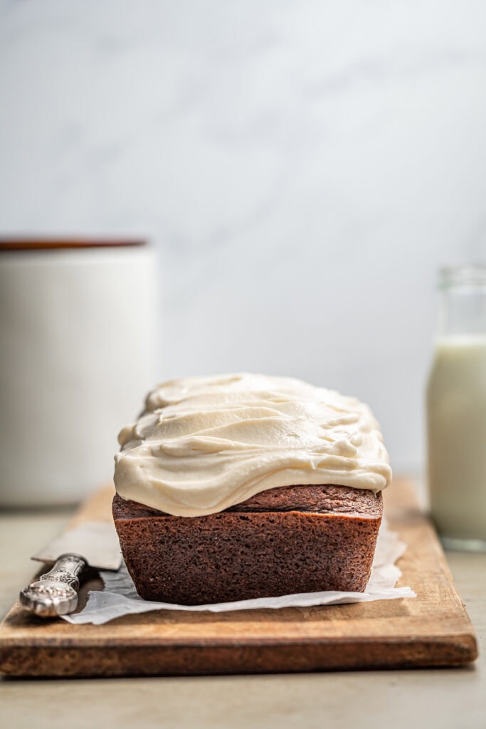 Moist chocolate loaf cake with creamy vanilla frosting on a wooden board, bakery dessert, homemade cake, sweet treat, Stuck On Sweet.
