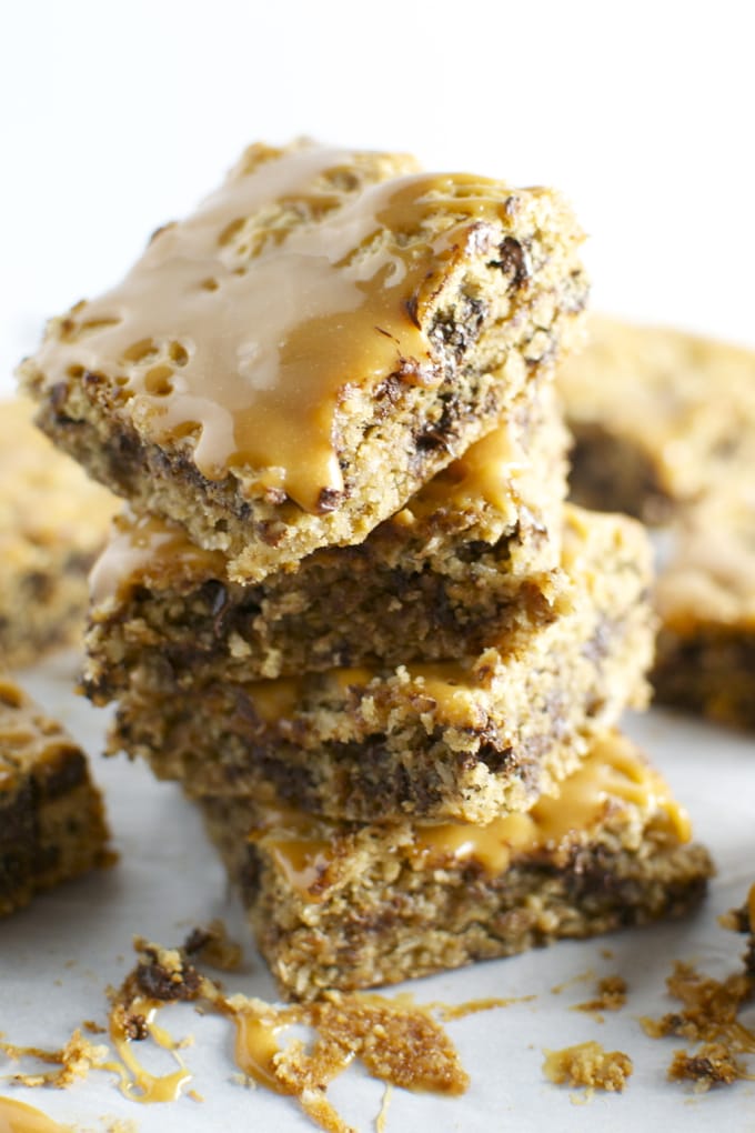 Stacked blonde cookie bars drizzled with caramel sauce, showcasing a chewy and gooey texture with chocolate chips, perfect for sweet snack cravings.