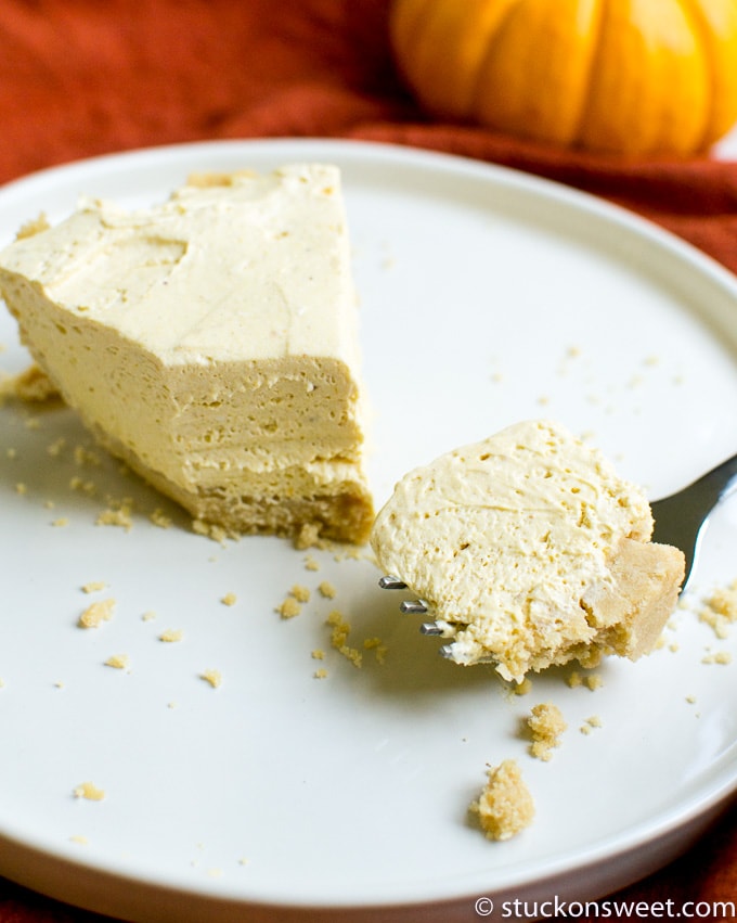 Creamy pumpkin cheesecake with a graham cracker crust on a white plate, perfect for fall dessert.