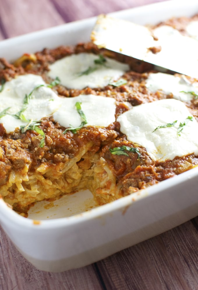 Creamy beef and noodle casserole with melted cheese and fresh herbs, baked to perfection, served in a white dish. Classic comfort food recipe perfect for family dinners.