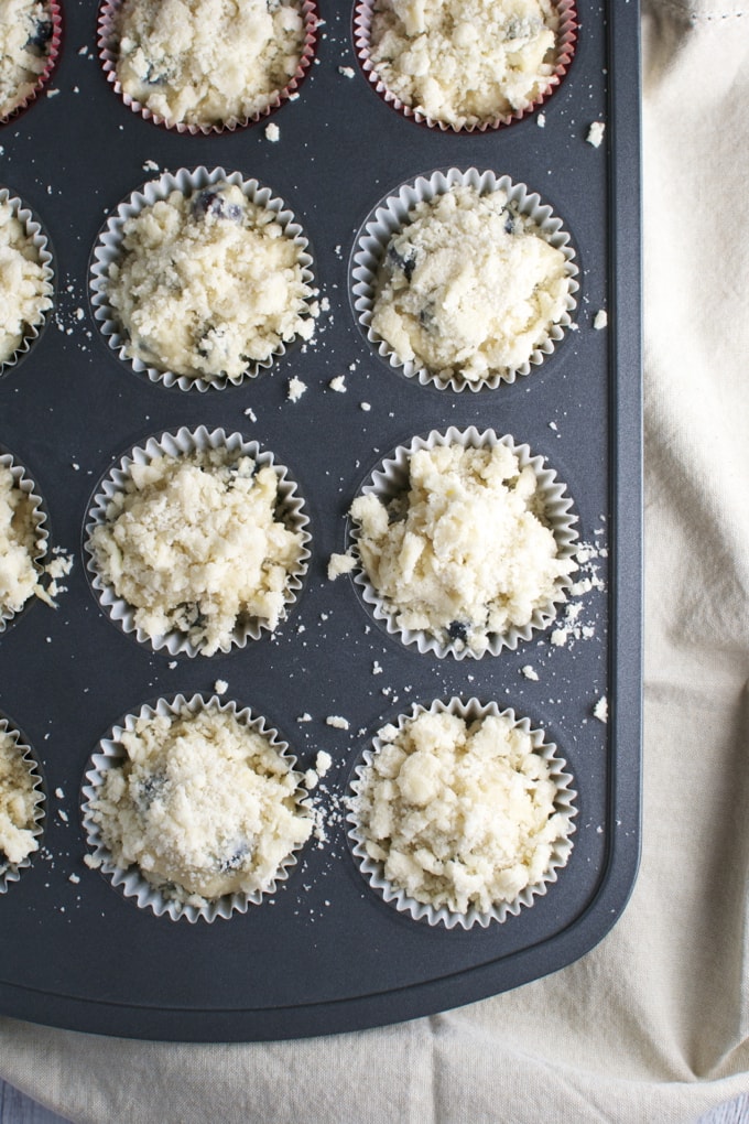 Buttermilk blueberry muffin batter in muffin tin with crumble topping, fresh blueberry muffins, baking process, homemade bakery, sweet breakfast treats.