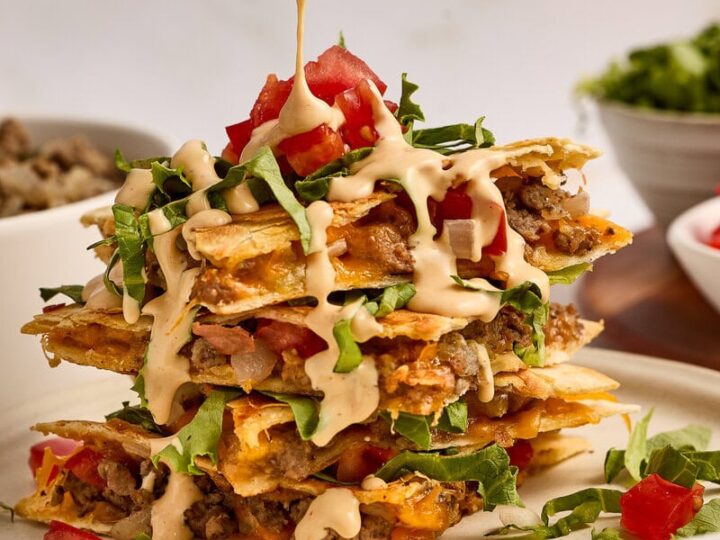 Delicious cheeseburger quesadillas stacked high with melted cheese, fresh tomatoes, lettuce, and savory beef, perfect for a flavorful meal.
