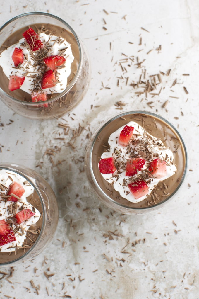 Creamy chocolate mousse topped with whipped cream, fresh strawberries, and chocolate shavings in glass desserts. Perfect for sweet cravings and dessert lovers.