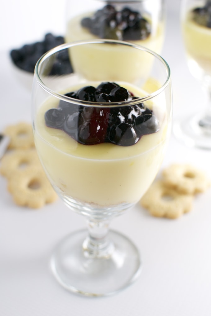 Creamy blueberry cheesecake dessert in a glass with fresh blueberries and berry compote, perfect for a sweet treat or dessert.