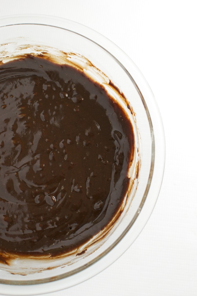 Rich chocolate frosting in a glass bowl, perfect for cake decorating or dessert topping. Smooth, glossy, homemade chocolate frosting for delicious sweet treats.